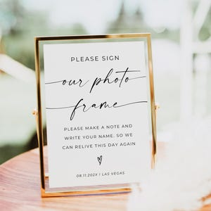 May include: A gold-framed sign with the text "PLEASE SIGN our photo frame." The sign also includes the text "PLEASE MAKE A NOTE AND WRITE YOUR NAME. SO WE CAN RELIVE THIS DAY AGAIN" and the date "08.11.202X I LAS VEGAS."