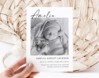May include: A black and white birth announcement card featuring a baby named Amelia. The card includes the baby's name, birth date, time, weight (17lbs 6oz), and length (20.1 in), along with a message from Julia and Robert.