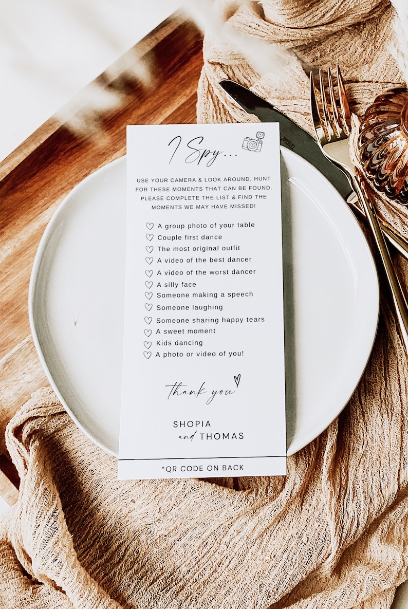 Peut inclure: Carte blanche avec du texte noir qui dit "I Spy..." et liste une s&eacute;rie d'activit&eacute;s li&eacute;es au mariage &agrave; photographier. La carte dit &eacute;galement "Merci" avec les noms "SHOPIA et THOMAS" et "*QR CODE AU DOS".