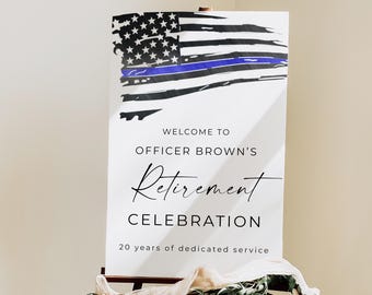 Puede incluir: Un letrero blanco sobre un caballete de madera con un diseño de bandera estadounidense desgastada con una línea azul. El letrero dice: "Bienvenida a la celebración de jubilación del oficial Brown, 20 años de servicio dedicado".