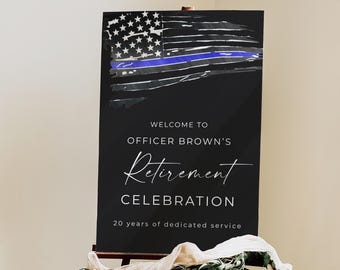 Puede incluir: Un letrero negro sobre un caballete de madera con un diseño de bandera estadounidense y una línea azul. El letrero dice "Bienvenida a la celebración de jubilación del oficial Brown" y "20 años de servicio dedicado."