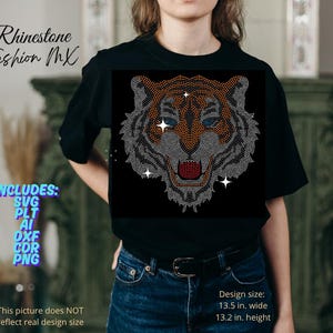 May include: Black t-shirt featuring a rhinestone tiger face design. The tiger's face is detailed with orange, silver, and red rhinestones. The design size is 13.5 inches wide and 13.2 inches high. Text on the shirt reads "Rhinestone Fashion MX".