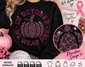 Może przedstawiać: Czarna bluza z długim rękawem z centralną grafiką dyni w różowo-czarny wzór panterki, otoczona napisem In October We Wear Pink wykonanym z różowych cyrkonii, z okrągłym zbliżeniem na detale z cyrkonii.