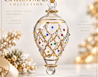 May include: A clear, hand-blown glass teardrop ornament featuring gold-painted horizontal bands and a delicate lattice pattern adorned with small, colourful embedded crystals in red, blue, green, and yellow, suspended by a gold ribbon.