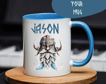 Puede incluir: Taza de cerámica blanca con borde y asa azules. La taza presenta un gráfico de un vikingo con barba y cuernos, y el nombre "JASON" está impreso sobre el gráfico.