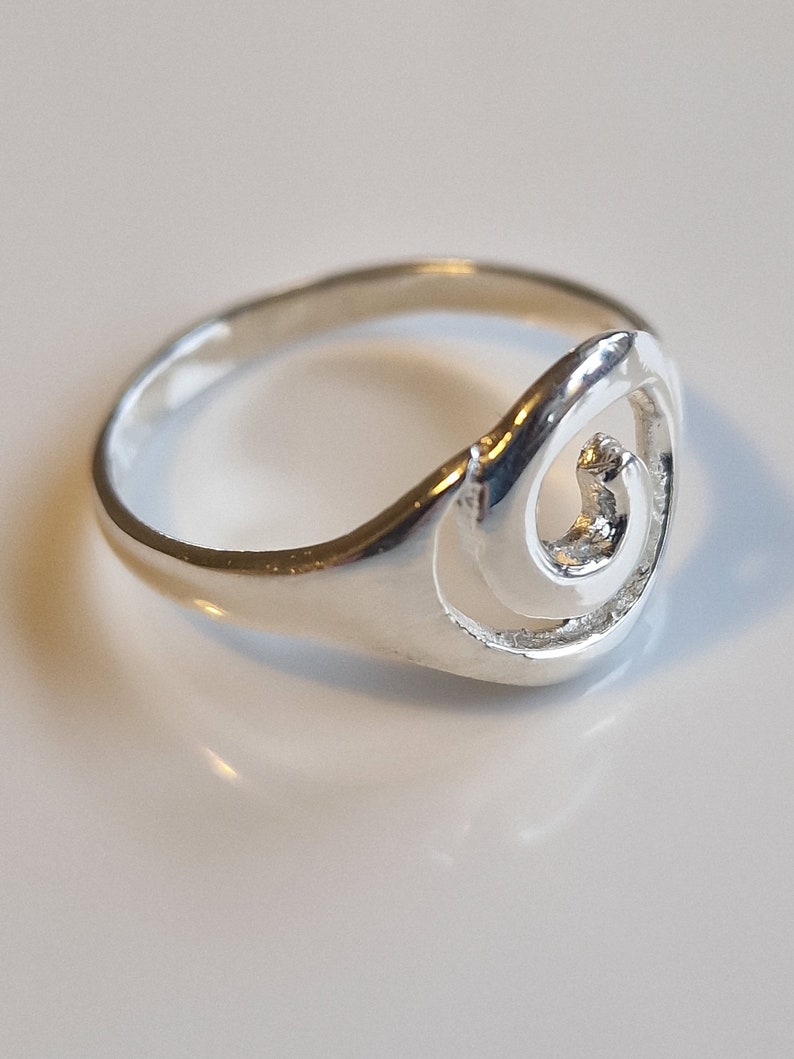 May include: A silver ring with a swirl design. The ring is simple and elegant.