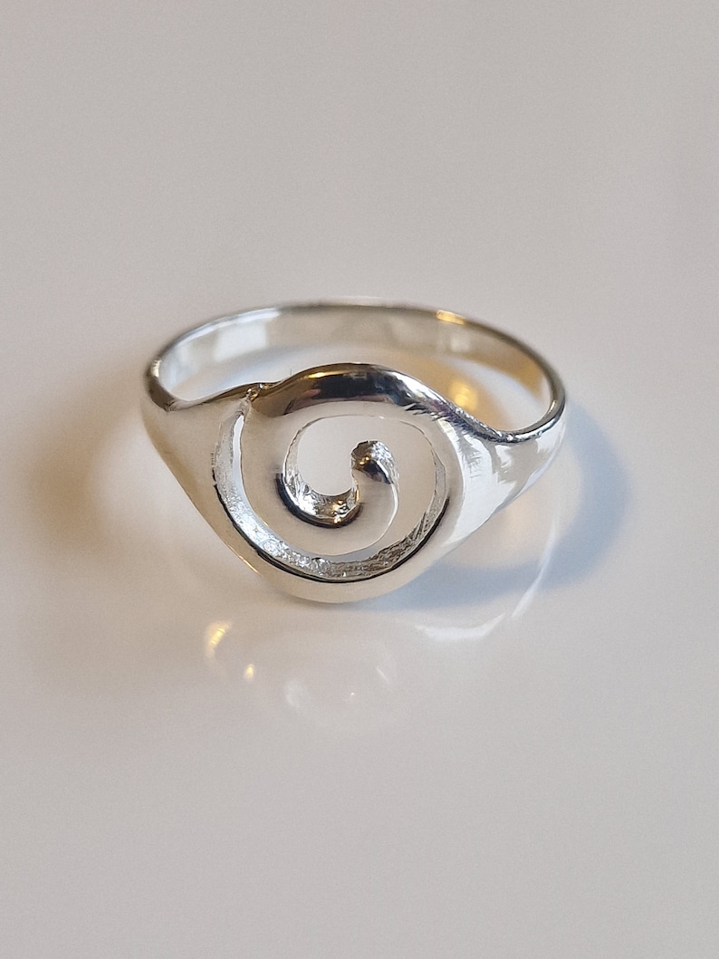 May include: A silver ring with a swirl design. The ring is simple and elegant.