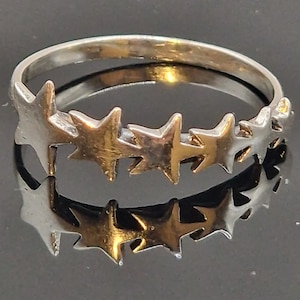 以下が含まれることがあります： バンドの周りに5つの星型の切り抜きが並んだシルバーリングです。