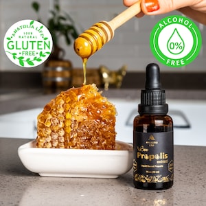 May include: A close-up of a honeycomb in a white dish with honey dripping from a wooden honey dipper. A brown glass bottle of "Bee Propolis extract" is next to the honeycomb. The image includes the text "100% Natural Gluten Free" and "Alcohol Free 0%".