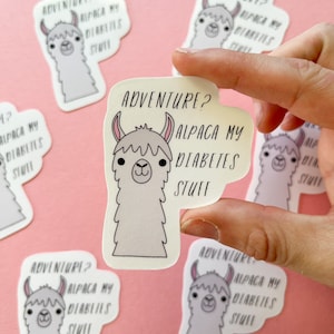 May include: A collection of white stickers with a cartoon alpaca design and the text "ADVENTURE? ALPACA MY DIABETES STUFF". The alpaca has a light gray body, pink ears, and a smiling face. The stickers are on a pink background.