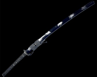 May include: A black katana sword with a white design on the blade. The sword is wrapped in black cord and has a black handle.