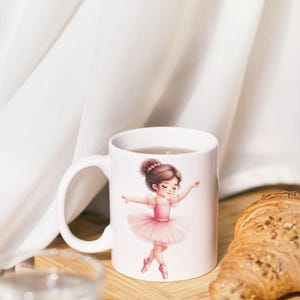 Op de afbeelding: Witte keramische mok met een ballerina in een roze tutu. De illustratie toont een jong meisje in een balletpose. De mok staat op een houten plank met een croissant. De achtergrond is een wit gordijn.