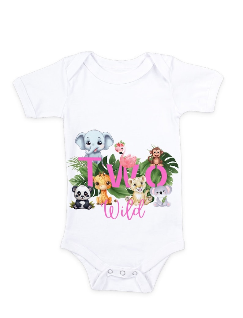 K&ouml;nnte beinhalten: Wei&szlig;er Baby-Strampler mit einem pinkfarbenen 'Two Wild'-Motiv, das verschiedene Dschungeltiere zeigt, darunter einen Elefanten, eine Giraffe, einen L&ouml;wen, einen Affen, einen Panda und einen Flamingo.