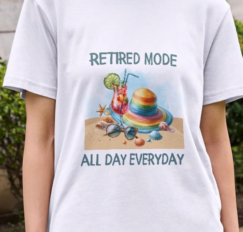 May include: White t-shirt with a colorful illustration of a beach scene and the text "Retired Mode All Day Everyday".