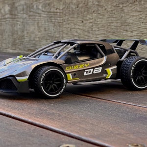 May include: A black and grey remote control toy car with yellow accents. The car has a roll cage and the words "Dizzy D8" printed on the side.