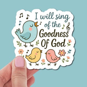 May include: A die-cut sticker featuring a light blue bird, a yellow chick, and a pink bird surrounded by small flowers and musical notes. The text reads, I will sing of the Goodness Of God, written in a dark brown script font on a white background.