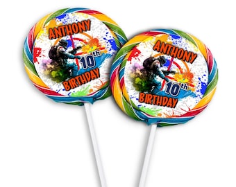 May include: Two round lollipops with colourful swirl designs and a white centre. The centre features a graphic of a person in camouflage holding a paintball gun with colourful paint splatters in the background. The text "ANTHONY 10th BIRTHDAY" is printed on the lollipop.
