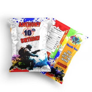 May include: A white chip bag with a paintball theme. The bag has a red, blue, and yellow paint splatter design. The front of the bag features a soldier holding a paintball gun. The text "ANTHONY 10th BIRTHDAY" is printed in red and blue. The back of the bag has a yellow and orange paint splatter design with the text "Thank You You Really Hit The Mark! ANTHONY".