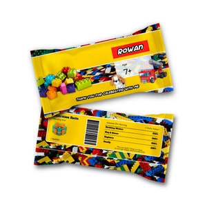 Puede incluir: Una bolsa de fiesta amarilla y roja con temática LEGO. La bolsa tiene una etiqueta de información nutricional con el texto "Birthday Wishes", "Hug & Kisses", "Happiness" y "Family". La bolsa también tiene el texto "ROWAN" y "Age 7+" en la parte delantera. La bolsa está decorada con ladrillos LEGO.