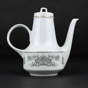 K&ouml;nnte beinhalten: Eine wei&szlig;e Porzellanteekanne mit konischem K&ouml;rper, geschwungenem Henkel und langem Ausguss. Der untere Teil ist mit einem schwarzen Blumenmuster verziert, w&auml;hrend der Deckel einen d&uuml;nnen Goldrand und einen kleinen Bogengriff besitzt.