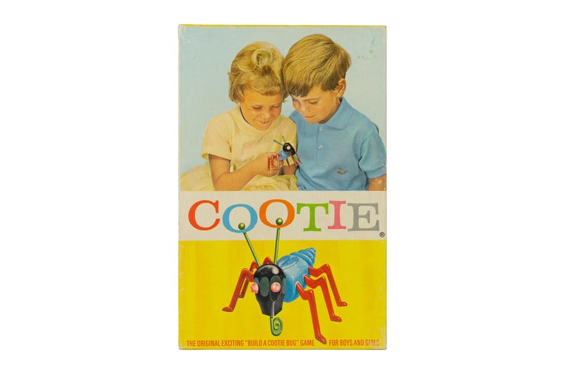 K&ouml;nnte beinhalten: Eine rechteckige Spieleschachtel f&uuml;r Cootie mit einer Grafik eines blauen, schwarzen und roten Kunststoffk&auml;fers mit gr&uuml;nen Antennen. Der obere Teil zeigt zwei Kinder, die mit dem Spielzeug spielen, w&auml;hrend unten der Titel und Text zu sehen sind.