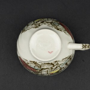 Pu&ograve; includere: Una tazza da t&egrave; in ceramica bianca vista dal basso, caratterizzata da una stampa paesaggistica in marrone e multicolore. La base presenta la scritta in rilievo MADE IN ENGLAND e un piccolo cuore rosa dipinto a mano vicino al bordo.