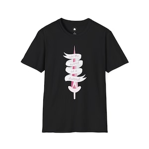 Puede incluir: Camiseta negra con un diseño de espada rosa y el texto "use the sword as a sword" en una pancarta blanca. El gráfico está centrado. La camiseta tiene mangas cortas y cuello redondo. Prenda de vestir informal.