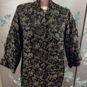 May include: A black and gold brocade robe with a traditional Chinese design. The robe has a mandarin collar and a button closure.