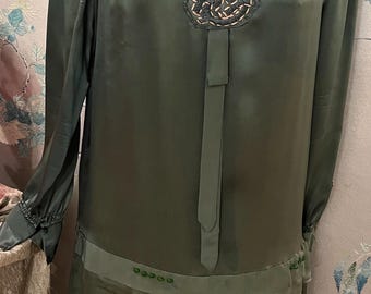 May include: A long-sleeved, green silk dress with a V-neckline and a decorative embellishment at the neckline. The dress has a pleated skirt and a fitted bodice.