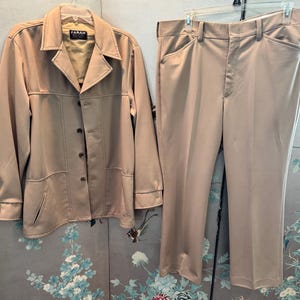 May include: A tan suit with a jacket and pants. The jacket has a button closure and a label that says "FARAH".