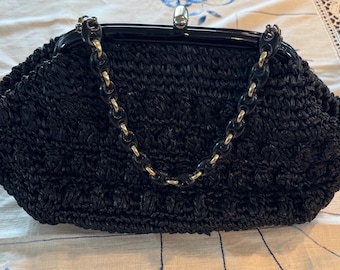 May include: A black woven straw handbag with a gold chain strap and a black plastic clasp.