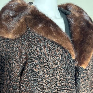 May include: A brown and black textured coat with a dark brown fur collar. The coat features a unique, patterned design and appears to be made of a soft, luxurious material. The collar is a rich, dark brown colour, adding a touch of elegance to the garment.