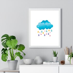 May include: A white framed print with a blue cloud with white stars and colorful raindrops falling from it.