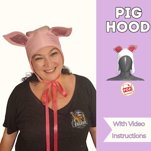 以下が含まれることがあります： 大きな垂れ耳とピンクのリボンが付いたピンク色の豚のフード。画像には、豚のフードの小さなイラストと「PIG HOOD」と「With Video Instructions」のテキストも含まれています。