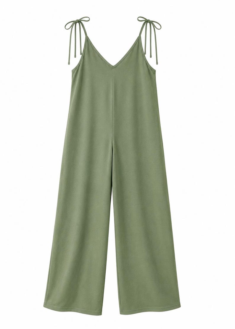 May include: A solid sage green jumpsuit featuring a V-neckline and wide-leg trousers. The garment includes thin shoulder straps that tie into bows at the top, providing an adjustable fit. The design is simple, sleeveless, and has a straight silhouette.