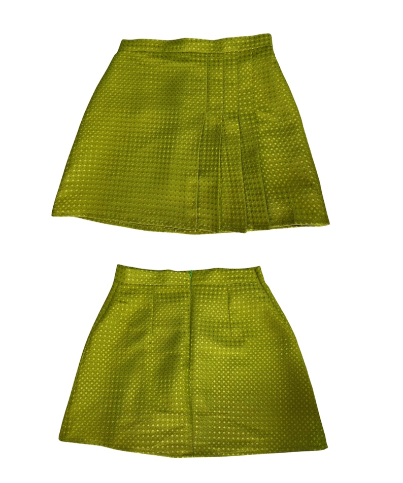 May include: A green mini skirt with a pleated front and a textured fabric. The skirt is shown from the front and back.