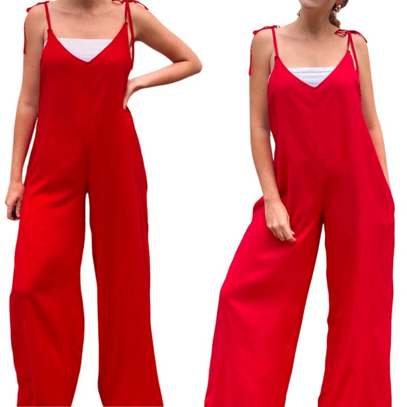 May include: A red wide-leg jumpsuit with thin straps and a V-neckline. The straps have ties at the shoulders.