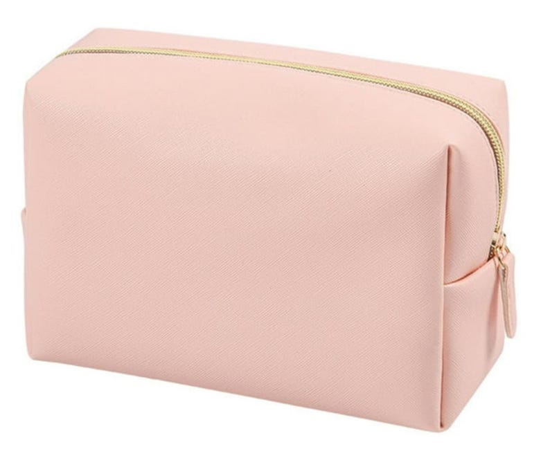 May include: A pale pink zippered makeup bag with a gold zipper.