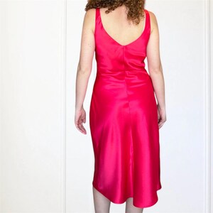 K&ouml;nnte beinhalten: Ein hellrosa Satin-Midikleid mit V-Ausschnitt und flie&szlig;endem Rock.