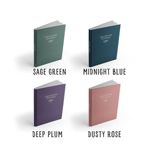 May include: Four hardcover journals with the text "Gratitude Journal" and a dragonfly design on the front cover. The journals are in four different colors: sage green, midnight blue, deep plum, and dusty rose.