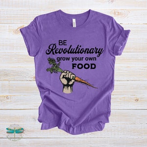 May include: Purple t-shirt with black text that reads "Be Revolutionary grow your own FOOD". A cartoon hand holding a carrot is printed on the shirt.