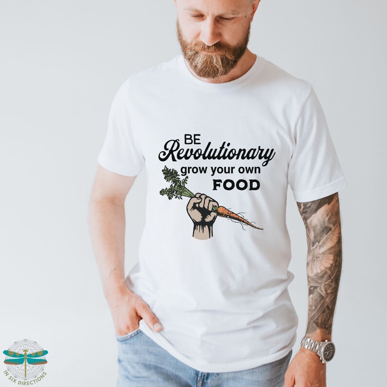 May include: White t-shirt with a black graphic of a fist holding a carrot and the text "BE Revolutionary grow your own FOOD".