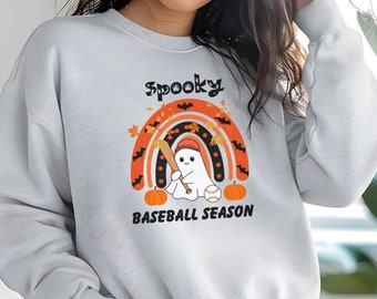 May include: A light gray sweatshirt with a colorful graphic that reads "Spooky Baseball Season." The design features a ghost holding a baseball bat under a rainbow with bats, leaves, and pumpkins.