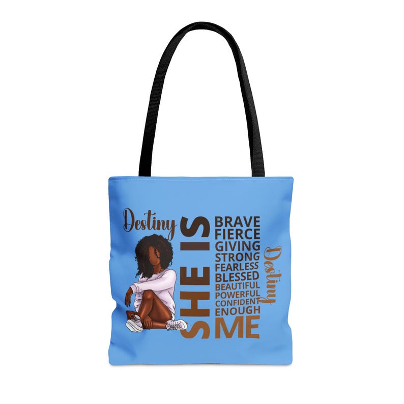 Pu&ograve; includere: Una borsa tote blu chiaro con un manico nero. La borsa presenta una grafica di una donna con la pelle marrone e i capelli neri. Il testo "Destiny SHE IS" &egrave; in lettere marroni e nere. Il testo "BRAVE FIERCE GIVING STRONG FEARLESS BLESSED BEAUTIFUL POWERFUL CONFIDENT ENOUGH ME" &egrave; in lettere marroni. Il testo "Destiny" &egrave; in lettere nere.