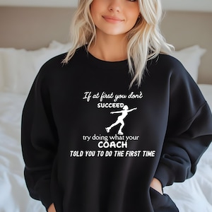 May include: Black sweatshirt with white text that reads "If at first you don't succeed, try doing what your coach told you to do the first time." The graphic includes a silhouette of a figure skater.