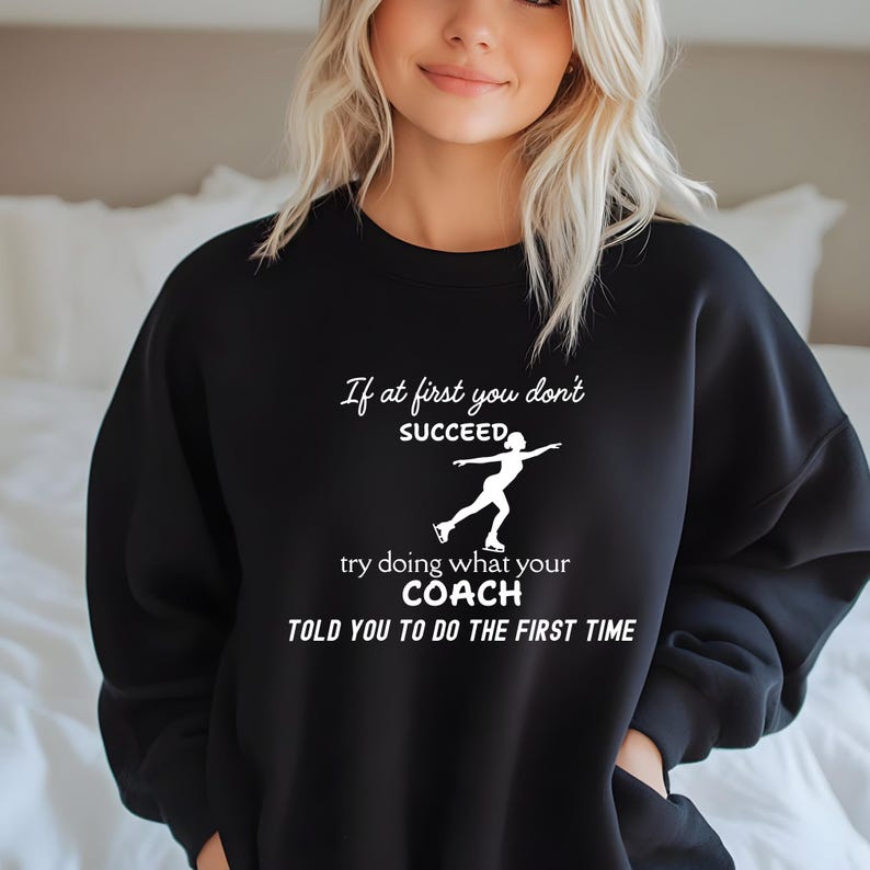 May include: Black sweatshirt with white text that reads "If at first you don't succeed, try doing what your coach told you to do the first time." The graphic includes a silhouette of a figure skater.