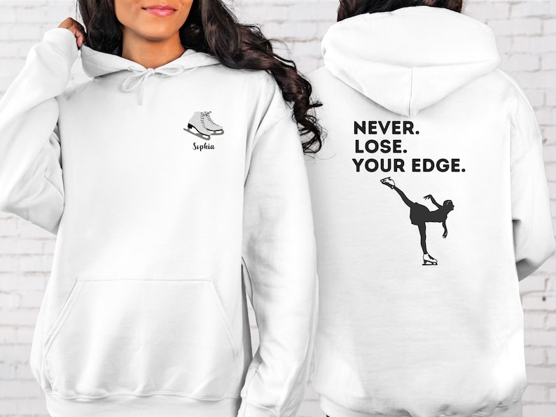 May include: White hoodie with a black silhouette of a figure ice skating on the back. The text "NEVER. LOSE. YOUR EDGE." is printed above the figure. The front of the hoodie has a pair of white ice skates and the name "Sophia" printed below.