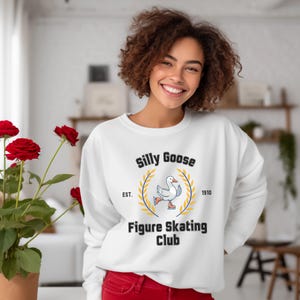 May include: White sweatshirt with a black and yellow logo that says "Silly Goose Figure Skating Club" with a cartoon goose wearing ice skates. The logo also says "Est. 1910".
