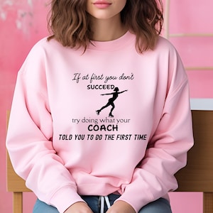 May include: A light pink sweatshirt with the text "If at first you don't succeed, try doing what your coach told you to do the first time." A black silhouette of a figure skater is also on the sweatshirt.