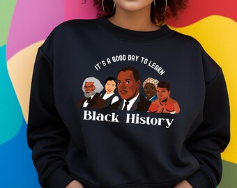May include: Black sweatshirt with a white graphic design featuring a quote "It's a good day to learn Black History" and illustrations of five prominent Black figures.